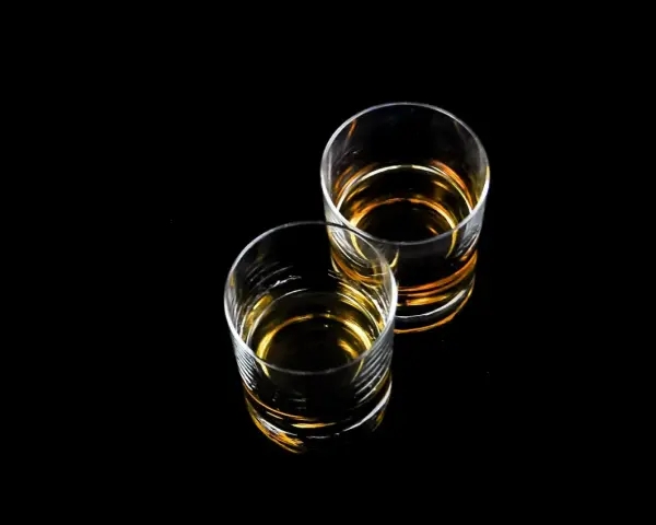 Dwa szklanki z bursztynowym płynem, idealne na wieczór z drinkiem. Czy to Baileys?