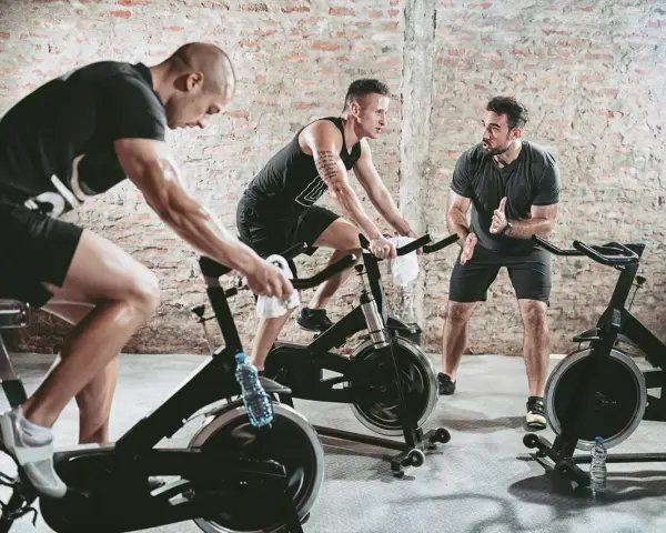 Trainer instructs men on stationary bikes. This workout can help build endurance, proving a stationary bike helps with running.