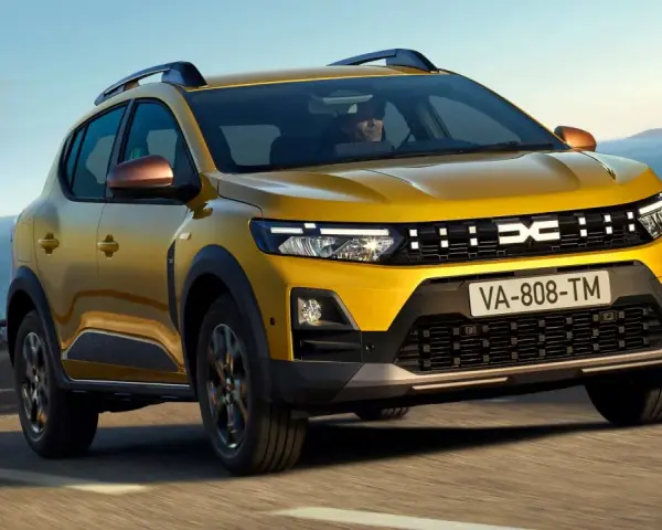 Żółty Dacia Duster, jeden z wielu popularnych dacia modele, jedzie po krętej drodze nad morzem.
