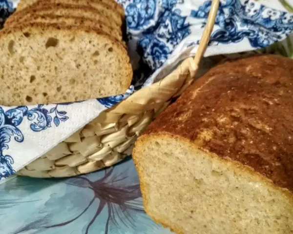 Chleb na piwie, świeżo upieczony, z chrupiącą skórką i puszystym wnętrzem. Kromki w koszyku, ozdobionym niebieskim wzorem.
