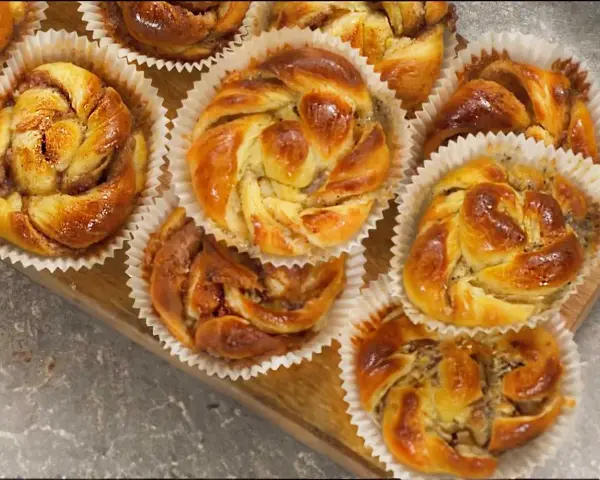 Nybakade bullar med mandelmassa och vallmofrön, gyllene och glansiga i sina pappersformar.