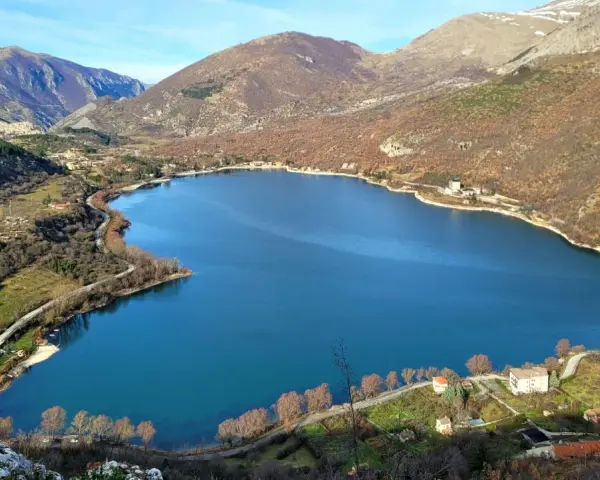 Panoramica del lago di Scanno, con montagne sullo sfondo e case sparse lungo la riva. Un luogo incantevole da esplorare.