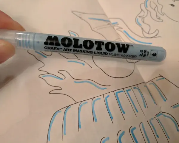 A hand holds a light blue Molotow Grafx Art Masking Liquid Pump Marker over a drawing.