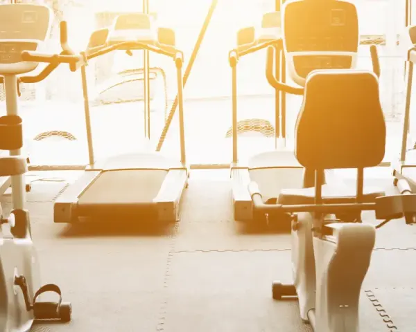 Rzędy bieżni i rowerów stacjonarnych czekają na trening. Idealne miejsce na cardio na siłowni, by poczuć energię.