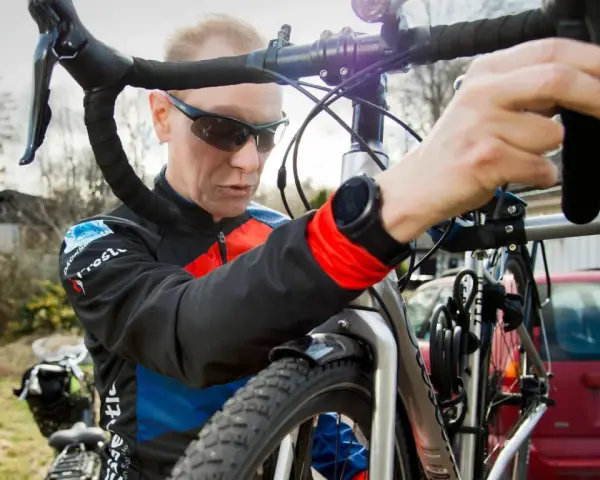 Man i cykelkläder fokuserar på att laga punktering på sin cykel.