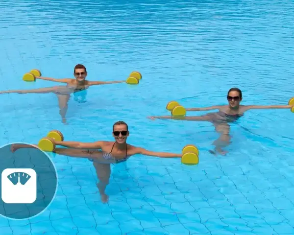 Trois femmes souriantes font un exercice aquagym dans une piscine, tenant des haltères flottants jaunes pour un entraînement tonique.
