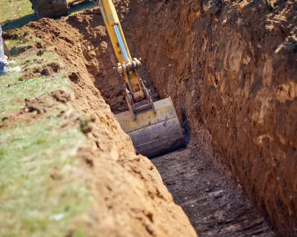Koparka pogłębia wykop pod garaż. Widać jaki głęboki fundament pod garaż powstaje.