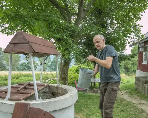 Mężczyzna czerpie wodę z **studni głębinowej**. Czy posiada **pozwolenie** na jej budowę?