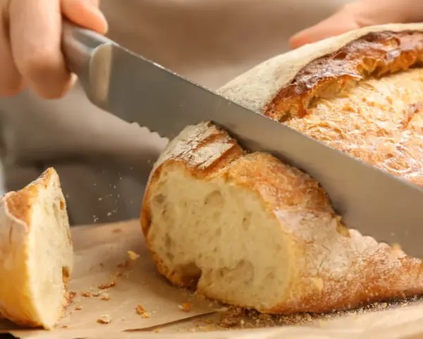 Krojenie świeżo upieczonego, domowego chleba. Ten przepis na chleb domowy pieczony w piekarniku jest idealny na każdą okazję.