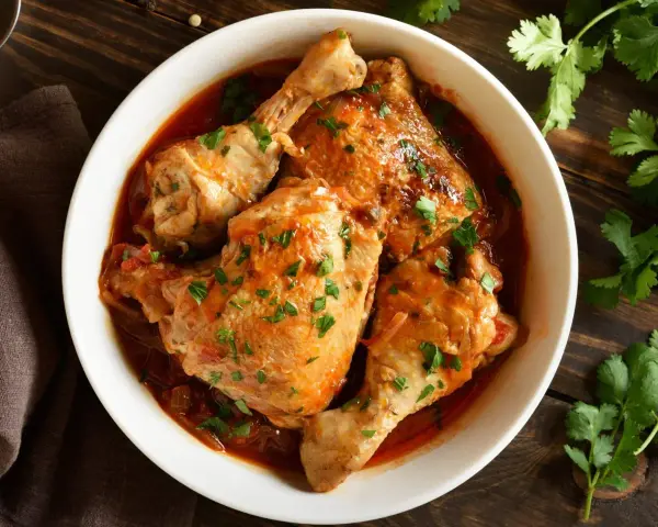 Soczyste kawałki kurczaka w aromatycznym, pomidorowym sosie, posypane świeżą natką pietruszki. Pyszny filet z kurczaka w sosie, gotowy do podania.