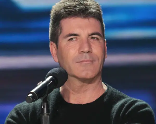 Simon Cowell, znany z surowych ocen, siedzi przy mikrofonie. Plotki o tym, że Simon Cowell nie żyje, są fałszywe.