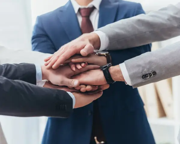 Zespół składa dłonie, symbolizując jedność i siłę. To jak prokura samoistna – wspólne działanie dla dobra firmy.