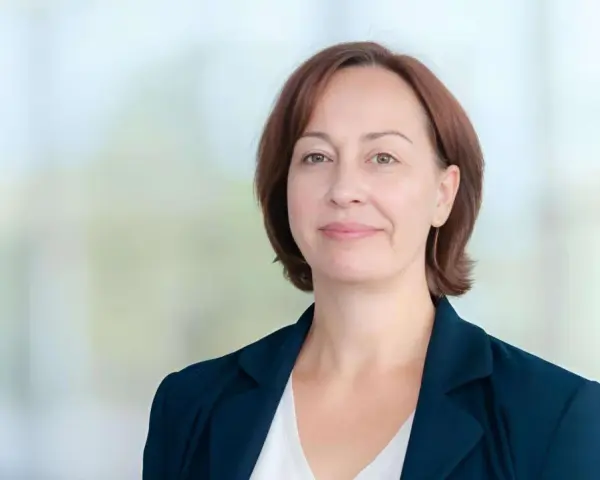 Agata Witkowska, aktorka, w granatowej marynarce i białej bluzce, uśmiecha się lekko.