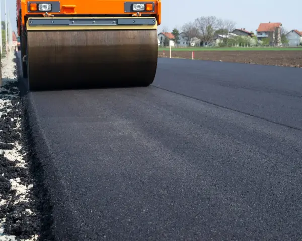 Walec drogowy ugniata świeży asfalt. Zastanawiasz się, ile kosztuje 1m2 asfaltu?