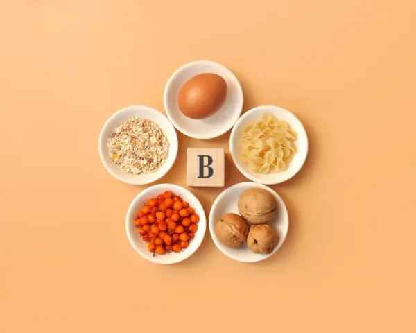 En ägg, havregryn, pasta, havtorn och valnötter arrangerade runt en träkub med bokstaven B, som symboliserar alla b-vitaminer.