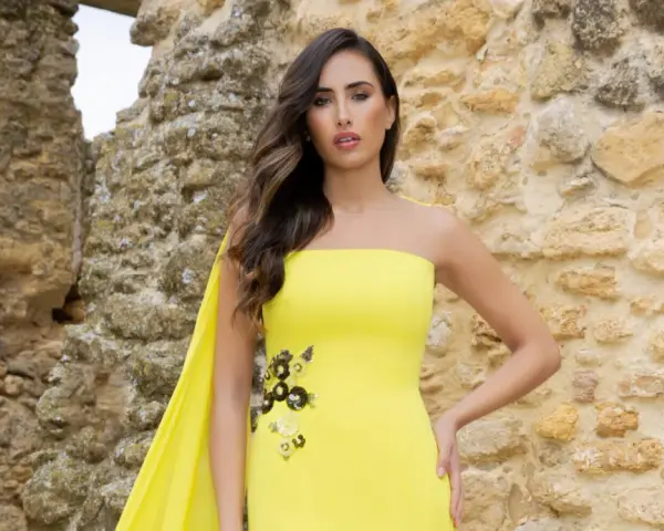 Mujer con vestido amarillo sin tirantes, con detalles florales y capa. Explora los diversos tipos de cuellos de vestidos.
