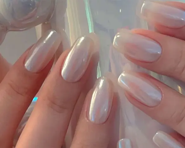 Mani eleganti con unghie a specchio perlate, che riflettono la luce con un effetto iridescente e sofisticato.
