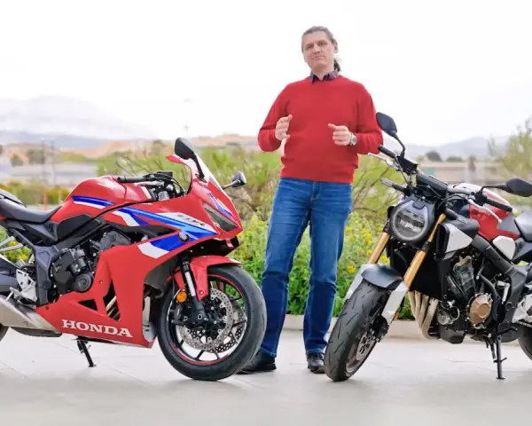 Mężczyzna w czerwonym swetrze prezentuje dwa motocykle Honda: sportowy CBR i naked bike CB650R.