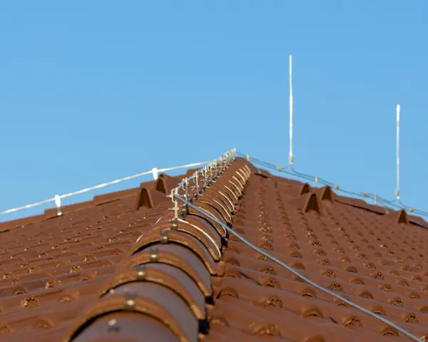 Nowy dach z brązowej dachówki, na którym zamontowano nowoczesną instalację odgromową, chroniącą przed burzami.