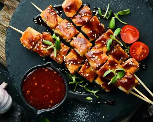 Hähnchenspieße mit glänzender Teriyaki-Sauce, Sesam und Kirschtomaten. Ein köstliches teriyaki sauce rezept zum Nachmachen.