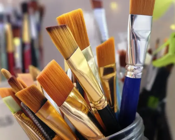 Un assortiment de pinceaux de peinture, prêts pour le nettoyage. Leurs poils orangés et leurs manches dorés brillent, attendant de retrouver leur éclat.