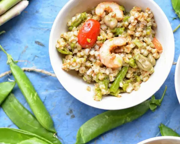 Deliziosa insalata di cereali con gamberetti, pomodorini, asparagi e fave. Un piatto fresco e nutriente.