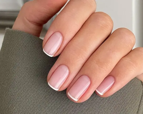 Dłoń z idealnymi, różowymi paznokciami i białymi końcówkami – klasyczne french nails.