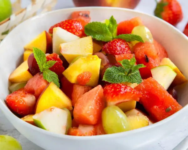 Ein bunter Obstsalat mit Erdbeeren, Melone, Pfirsich und Trauben – ein einfaches obstsalat rezept für heiße Tage.