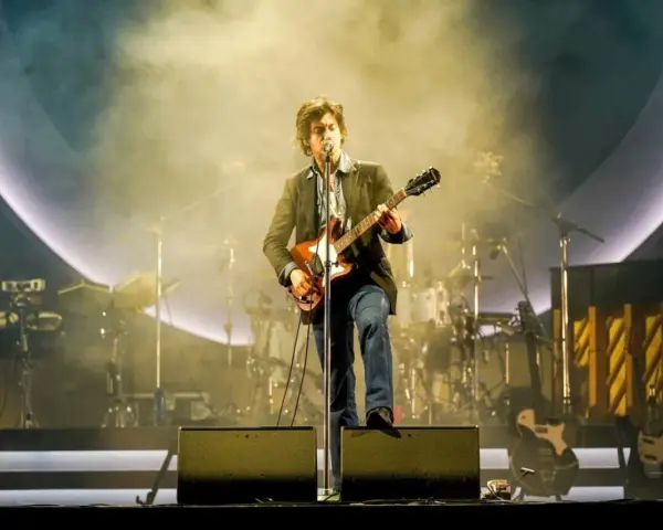 Alex Turner z Arctic Monkeys Polska na scenie, grając na gitarze w otoczeniu dymu i świateł.