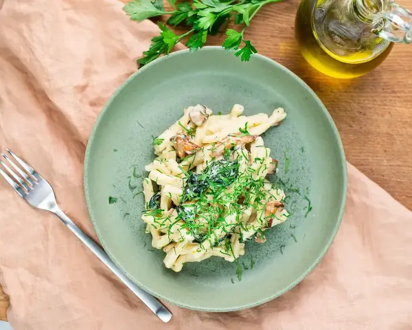 Krämig svamp pasta med färska örter på en grön tallrik, redo att avnjutas.