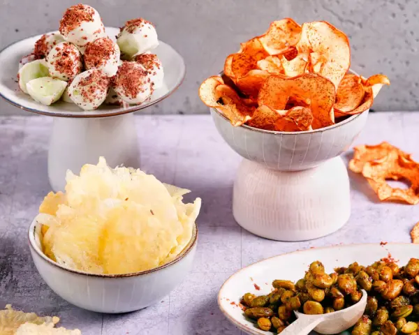 Leckere filmabend snacks: weiße Schoko-Bällchen, Apfelchips, knusprige Cracker und gewürzte Edamame.