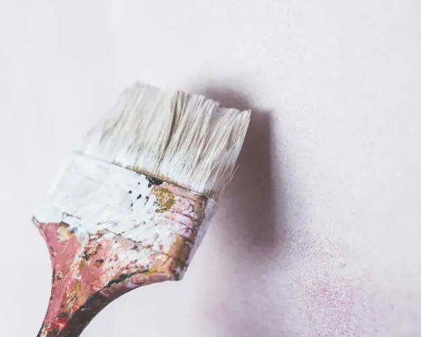 Pincel con restos de masilla para pared interior, listo para renovar.
