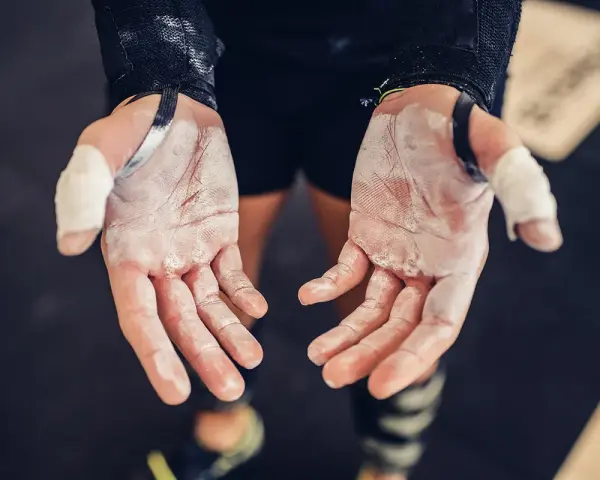 Mains de sportif couvertes de magnésie, témoignant d'une main calleuse et d'un entraînement acharné.