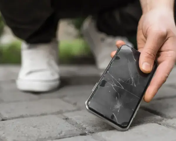 Zepsuty ekran telefonu leży na chodniku. Zastanawiasz się, ile kosztuje naprawa aparatu w telefonie po takim wypadku?