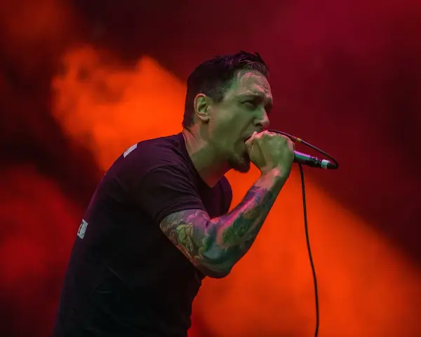 Chanteur au micro, le regard intense, comme s'il en avait marre de tout. Lumières rouges et orangées.