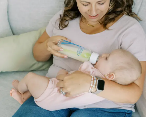 Kiedy zmienic przeplyw smoczka? Mama karmi dziecko butelką, obserwując, czy maluch nie ma problemów z jedzeniem.