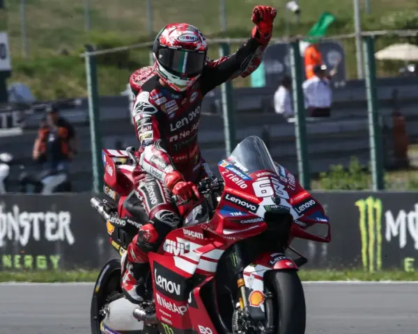 Piloto de MotoGP celebra victoria en su moto Ducati roja. Aunque no se especifica cuanto mide Marc Márquez, su presencia en la pista es imponente.