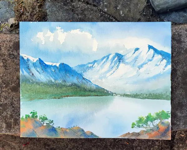 Pintura de montañas nevadas y un lago sereno, mostrando como se pinta con acuarela. Nubes blancas flotan en un cielo azul.