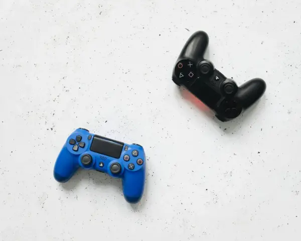 Dos mandos de videojuego, uno azul y otro negro, listos para una intensa sesión de videojuego de acción y aventura.