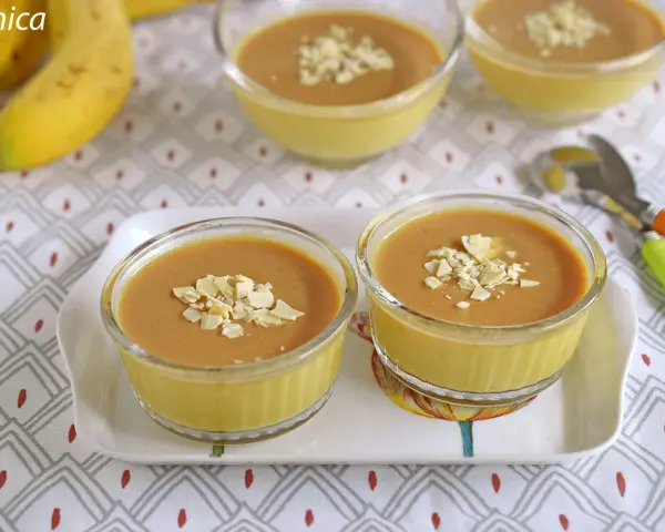 Postres de plátano en copas de cristal, decorados con láminas de almendra.