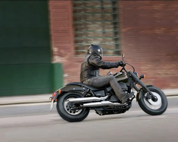 Motocyklista na Honda Shadow 750, z uwzględnieniem danych technicznych, pędzi ulicą.