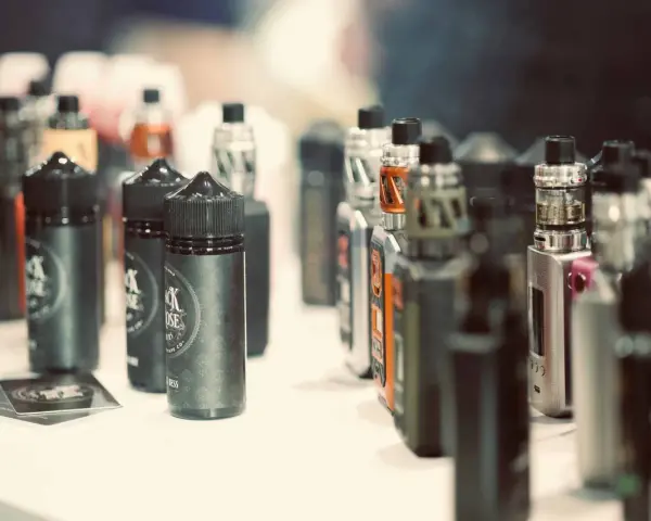 Botellas de líquidos para vapear, con diversos potenciadores de sabor, y dispositivos electrónicos en exhibición.