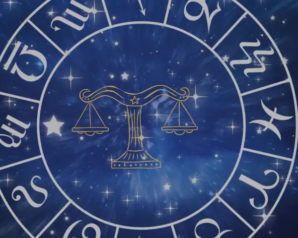 Złoty symbol wagi, jeden z dwunastu znaków zodiaku, na tle gwieździstego, niebieskiego kosmosu.