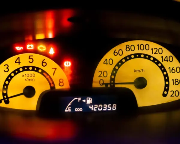 Cruscotto auto con spie accese: olio, batteria, motore, cinture, freno. Tachimetro e contagiri gialli. Display mostra temperatura, livello carburante e chilometraggio. È ora di controllare TPMS.