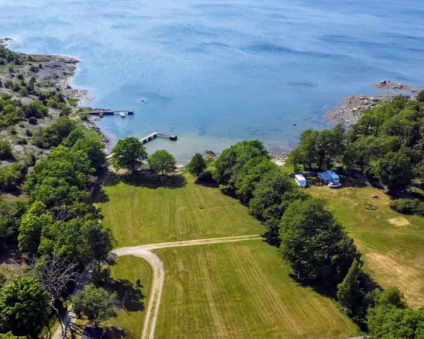 Vacker vy över camping i Blekinge med husvagnar vid en brygga och grönskande skog.