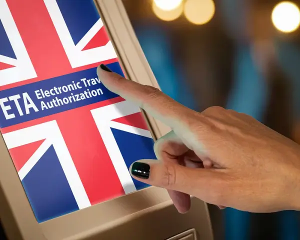 Dłoń naciska ekran z flagą Wielkiej Brytanii i napisem ETA Electronic Travel Authorization. To krok do uzyskania wizy do Anglii.