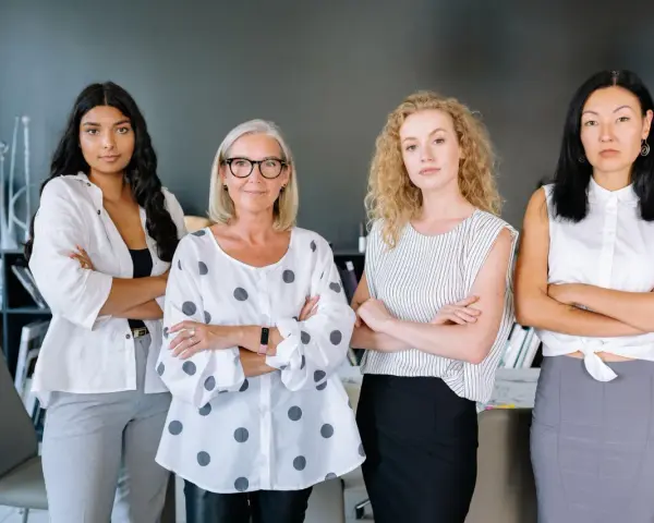 Cuatro mujeres emprendedoras, diversas en edad y etnia, posan con confianza en una oficina.