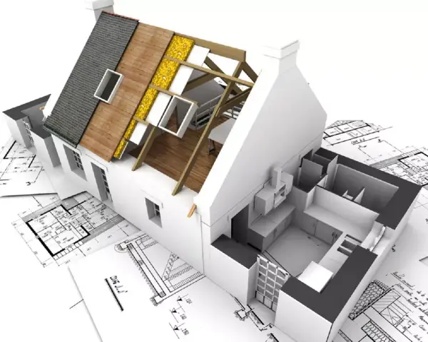 Maquette d'une maison en cours de rénovation, montrant la structure du toit et l'intérieur, posée sur des plans d'architecte. Un projet pour réhabiliter une maison.