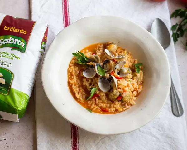 Delicioso arroz con berberechos, preparado con arroz redondo Sabroz, adornado con perejil fresco.