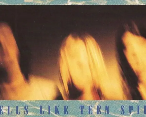 Rozmyte postacie, jakby w ruchu, na tle sugerującym okładkę albumu "Smells Like Teen Spirit" Nirvany.